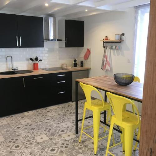 a kitchen with yellow chairs and a wooden table at Maison au cœur des étangs de Sologne avec SPA , Domaine de Sainte-Marie in Ardon