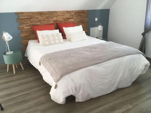 1 dormitorio con 1 cama grande con almohadas rojas y blancas en Maison au cœur des étangs de Sologne avec SPA , Domaine de Sainte-Marie, en Ardon
