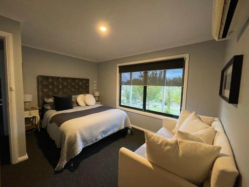 a bedroom with a bed and a couch and a window at East Jindabyne- Cavallino 4 bedroom home in Jindabyne