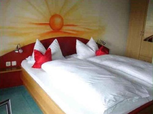 a bedroom with a white bed with red pillows at Landhotel Waldesruh in Furth im Wald