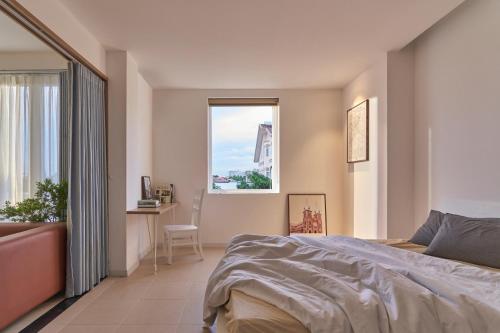 a bedroom with a bed and a desk and a window at M Village Living Nguyễn Văn Hưởng in Ho Chi Minh City