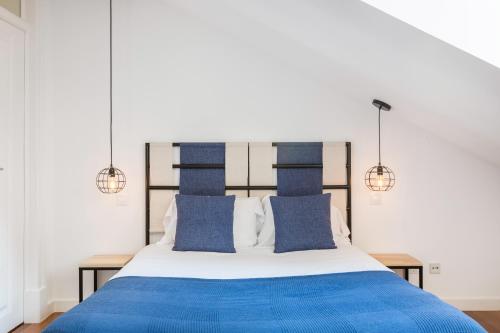 a bedroom with a blue and white bed with two lights at Stunning and Spacious Lofts just by Graça and Alfama in Lisbon