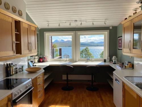 uma cozinha com uma grande janela com vista para a água em Great house with amazing location!!Sea & mountain view! em Kvaløya