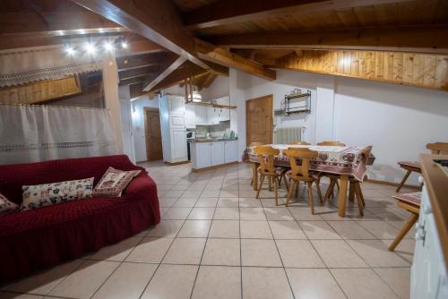 salon ze stołem i czerwoną kanapą w obiekcie appartamento val di sole w mieście Dimaro