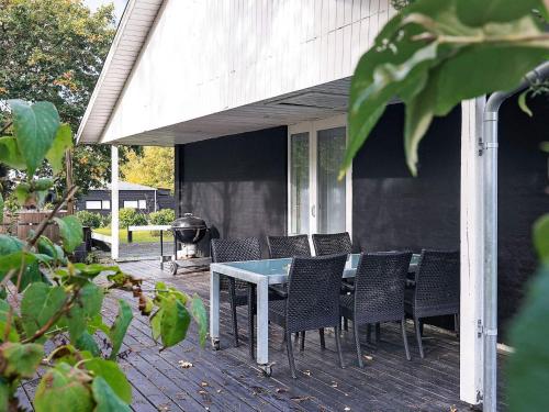 eine Terrasse mit einem Tisch, Stühlen und einem Grill in der Unterkunft 8 person holiday home in Skals in Skals