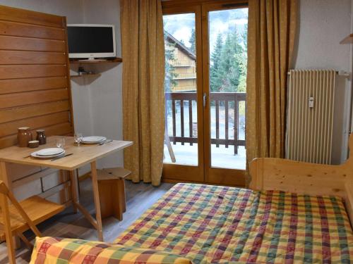 1 dormitorio con cama, mesa y balcón en Appartement Méribel, 1 pièce, 2 personnes - FR-1-180-567, en Les Allues