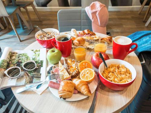 una mesa con comida para el desayuno y bebidas en ella en ibis Orléans Nord Saran, en Saran