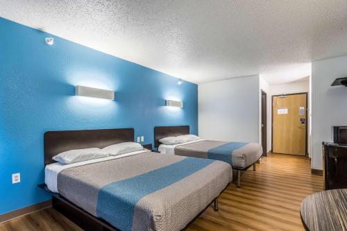 2 camas en una habitación con una pared azul en Motel 6-Indianapolis, IN - Southport, en Indianápolis