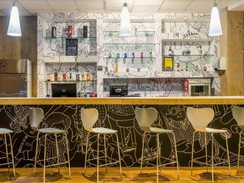 a bar with chairs and a wall covered in graffiti at ibis Uberaba in Uberaba