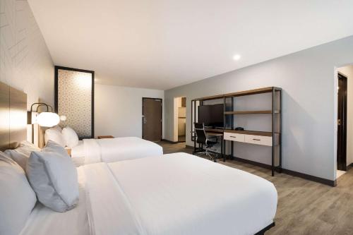 um quarto de hotel com duas camas e uma secretária em Everhome Suites Corona em Corona