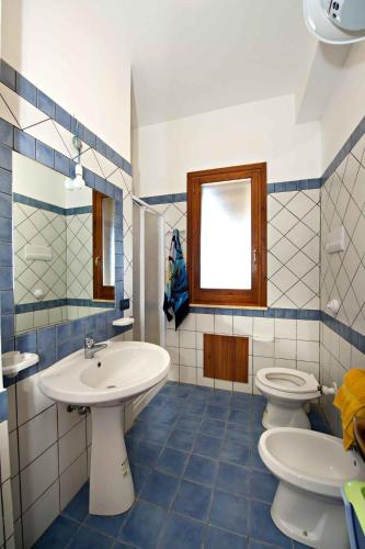a blue and white bathroom with two toilets and a sink at Blunda Holiday Home in Castellammare del Golfo