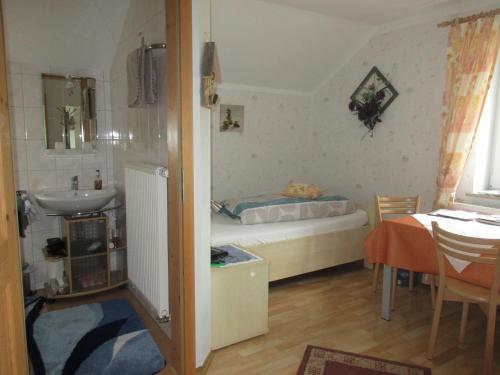 a bedroom with a bed and a sink and a table at Gästehaus Reisacher - Einzelzimmer in Peiting
