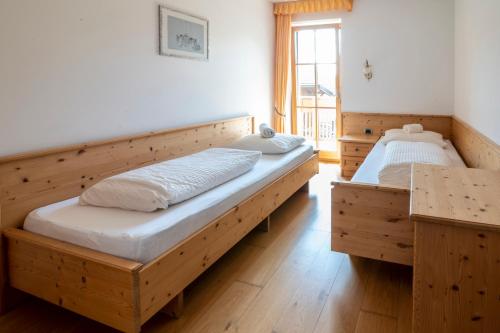 two beds in a room with wooden floors at Gruberhof Coll in Funes