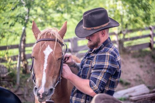 a man wearing a cowboy hat petting a horse at Gruberhof Coll in Funes