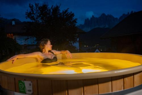 a woman is sitting in a hot tub at Gruberhof Coll in Funes
