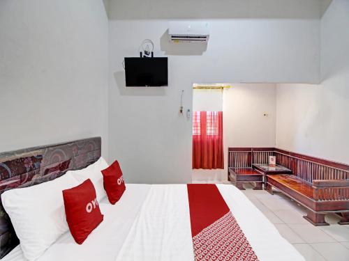 - une chambre avec un lit doté d'oreillers rouges et blancs dans l'établissement Capital O 91690 Moza Guest House, à Klaten