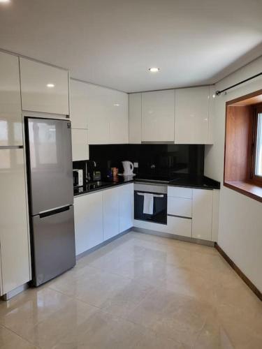 a kitchen with white cabinets and a stainless steel refrigerator at Maison Fernandes in Bustelo