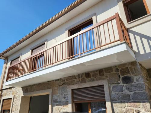 a balcony on a house with a stone wall at Maison Fernandes in Bustelo