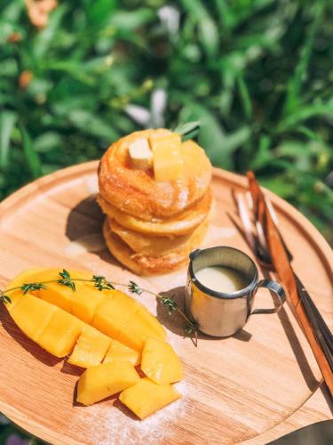 a wooden tray with a plate of food with cheese and pineapple at Tanouy Garden in Baan Khai