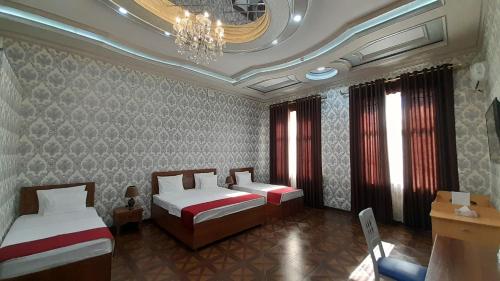 a hotel room with two beds and a chandelier at Villa Oasis in Bukhara