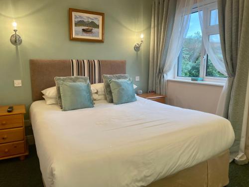 a bedroom with a large white bed with blue pillows at Buttermilk Lodge in Clifden