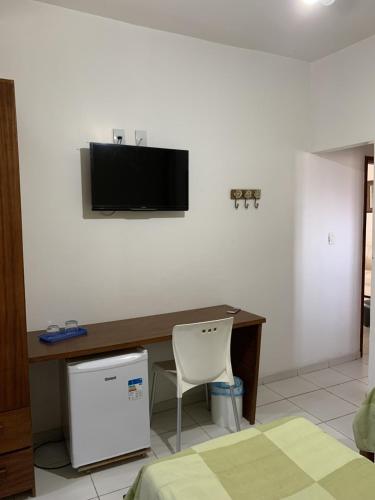 a room with a desk with a television on the wall at Pousada Alice in Cabo Frio