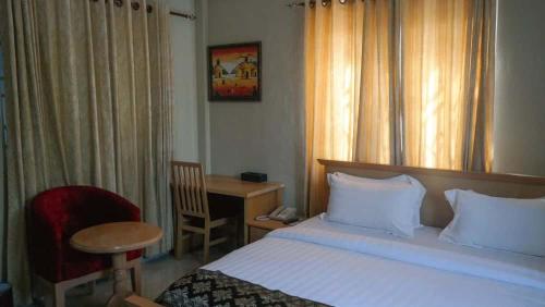 a bedroom with a bed and a desk and a chair at Yakam Hotel Limited in Kintampo