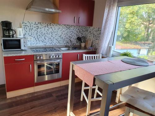 ノルデンにあるLütje Hörnの赤いキャビネットとテーブル、窓付きのキッチン