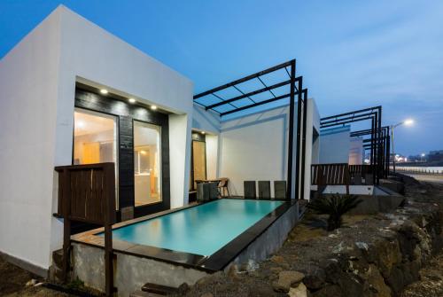 a house with a swimming pool in front of it at Aqua Beautique Poolvilla in Jeju