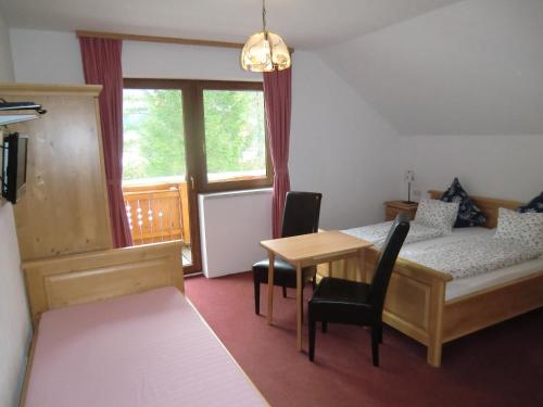 a bedroom with a bed and a table and a window at Haus Rye in Obertraun