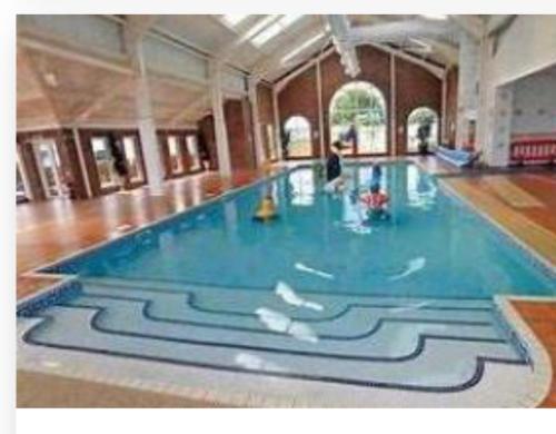 a large swimming pool with blue water in a building at Robin hood Caravan park North Wales Free Wi-Fi and Smart TVs Passes not included in Rhyl