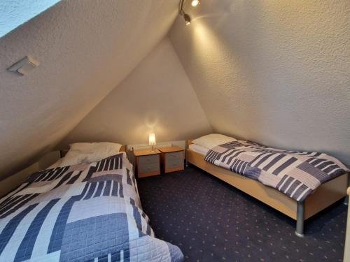 a bedroom with two beds and a table with a lamp at Ferienhaus Steuerbord im Bootshaus in Neßmersiel