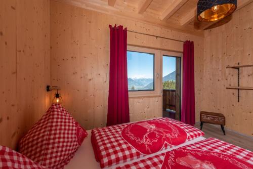 twee bedden in een kamer met rode gordijnen en een raam bij Heustadl in Zell am Ziller