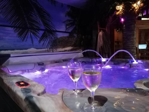 two glasses of wine sitting on a table next to a hot tub at Au clair de lune in Chavelot