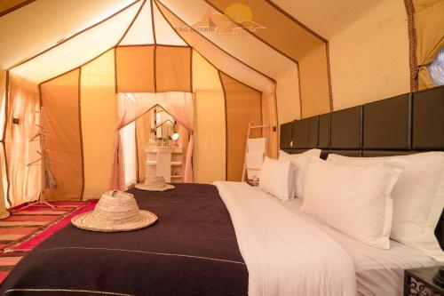 ein Schlafzimmer mit einem Bett mit Strohhut darauf in der Unterkunft Erg Chebbi Camp in Merzouga