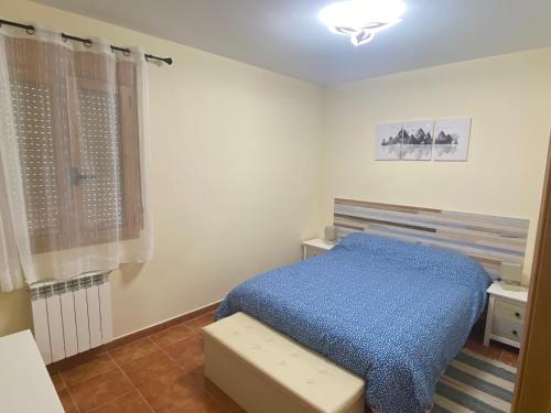 a bedroom with a blue bed and a window at Casa La Fontana Bronchales in Bronchales