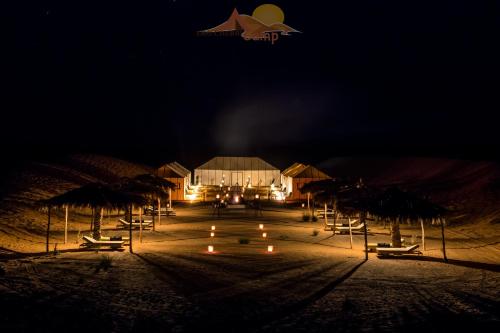 una spiaggia con sedie e ombrelloni di notte di Erg Chebbi Camp a Merzouga