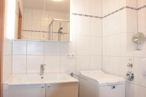 a white bathroom with a sink and a toilet at StrandGut in Boltenhagen
