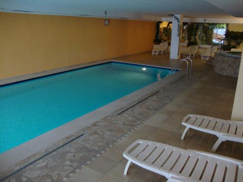 ein Pool mit zwei Chaiselongues und einem Pool in der Unterkunft Wellness e Resort Stella Delle Alpi in Ronzone