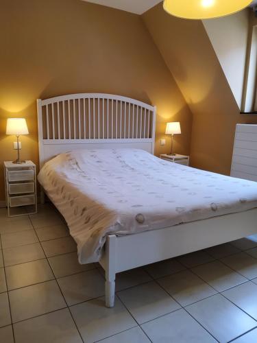 a white bed in a room with two lamps at Vakantiehuis in Knokke-Heist met tuin en parkeerplaats in Knokke-Heist