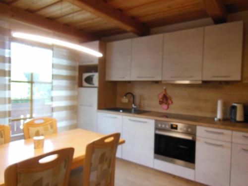 una cocina con armarios blancos y una mesa con sillas. en Haus Spannbauer, en Neureichenau
