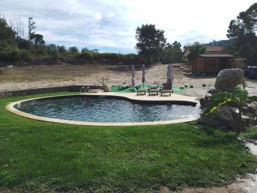 uma piscina com cadeiras e guarda-sóis num quintal em Q.ta Moinhos da Ponte na Tábua