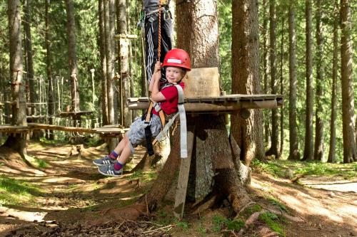 a young boy sitting on a rope swing in the woods at Ferienwohnung Haus Annabelle Top 3 in Damuls