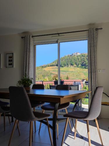 a dining room with a table and chairs and a large window at Gite des Cépages in Voiteur