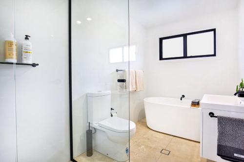 a white bathroom with a toilet and a bath tub at Zen @ Culburra - Pet Friendly - 8 Mins to Beach in Culburra Beach
