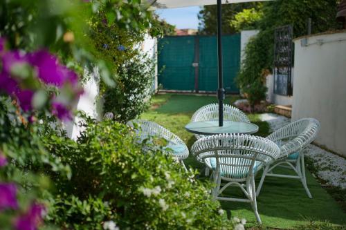 three chairs and a table in a yard with flowers at Lake&More in Trevignano Romano