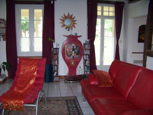 ein Wohnzimmer mit einer roten Couch und einer Uhr in der Unterkunft Grande maison atypique in Le Burgaud