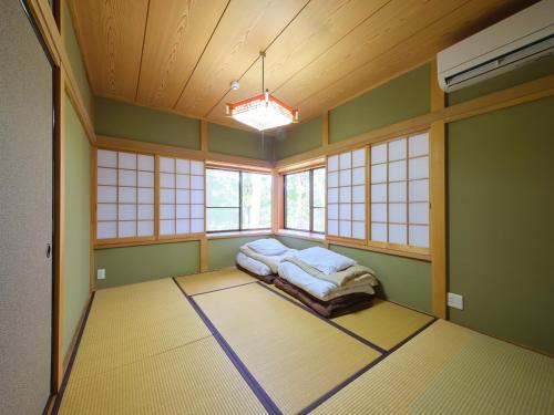 a bedroom with a bed in a room with windows at HARUNA WING Private cottage in the forest overlooking the golf course in Tsumagoi