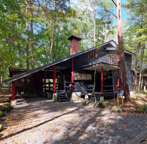 a black cabin with a chimney in the woods at HARUNA WING Private cottage in the forest overlooking the golf course in Tsumagoi