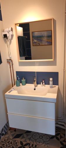 une salle de bain avec un lavabo blanc et un miroir dans l'établissement LA SAPINIERE, à Cabourg